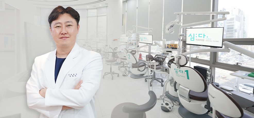 심:다 로고 모니터와 '심:다 1/2' 체어가 있는 진료실 앞 김영덕 대표원장 팔짱 사진