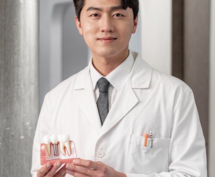 임플란트 모형을 든 흰 가운의 남성 의사 모델